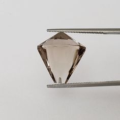 a diamond being cut into smaller pieces on a piece of metal with two tongs