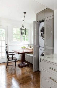 a washer and dryer in a room with wood floors, cabinets, and a dining table