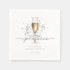 a glass of champagne on top of a white napkin with confetti around it