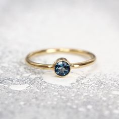 a gold ring with a blue topazte in the center on a white background