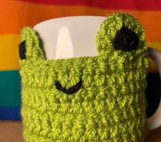 a green crocheted mug cozie with eyes