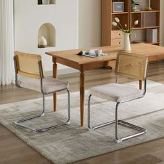 a dining room table with two chairs and a rug on the floor in front of it