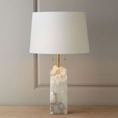 a marble lamp on a wooden table with a white lampshade next to it