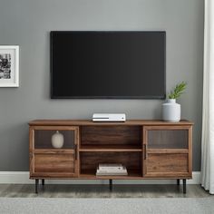 a flat screen tv sitting on top of a wooden entertainment center next to a window