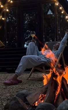 a man sitting in a chair next to a fire pit with his feet on the ground