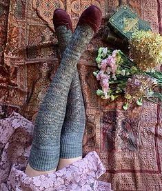 a woman laying on top of a bed with her feet up next to a bouquet of flowers