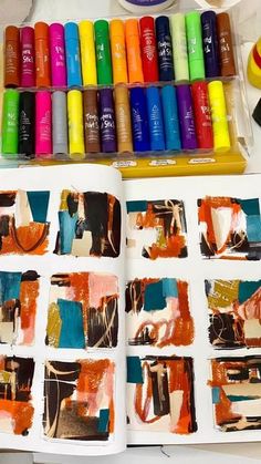 an open book with many different colors of paint on it and some crayons next to it