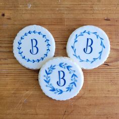 three decorated cookies with the letters b, c, and d on them sitting on a wooden table