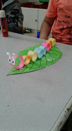 a paper plate with a caterpillar on it sitting on top of a table