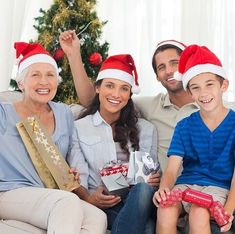 a group of people sitting on top of a couch with christmas presents in front of them