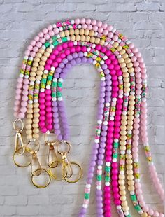 a bunch of beads that are next to each other on a brick wall with two pairs of scissors hanging from them