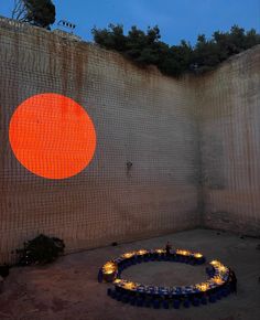 a circular fire pit in front of a wall with an orange circle painted on it