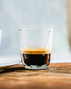 a glass filled with liquid sitting on top of a wooden table