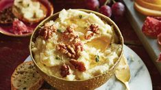 a bowl of mashed potatoes with walnuts and cranberries on the side