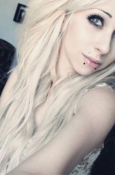 a woman with long blonde hair and piercings posing for a photo in her living room