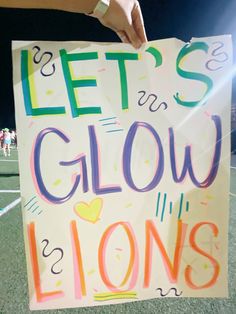 a hand holding a sign that says let's glow lions