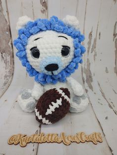 a crocheted lion holding a football on top of a wooden table with the word congratulations written below it