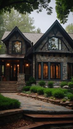 a stone house with lots of windows and steps leading up to the front porch area