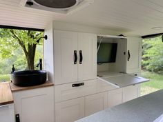 a kitchen area with cabinets, counter tops and a television mounted to the side of the wall