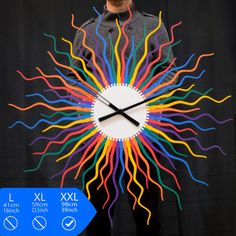 a man standing in front of a clock made out of colored streamers and sticks