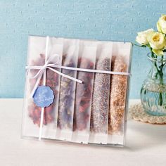 an assortment of dried flowers in a clear box with a blue tag on the front