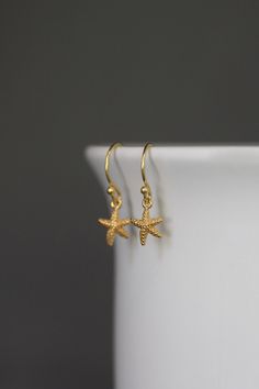 "Dainty and petite 24k gold vermeil starfish charms dangle from 18k gold vermeil balled earwires. Perfect small earrings for anyone of any age. Gold star charms: 8x9mm Total length of earrings: almost 1\" All gold is gold vermeil. As the owner, maker, designer, and curator of this shop, I take great pride in providing you with jewelry that you will love to wear everyday, for special occasions, and for many years to come. Please read my Shop Policies which contains important information regarding 14k Gold Filled Earrings With Star Charm As Gift, Everyday Yellow Gold Earrings With Star Charm, Yellow Gold Starfish Earrings For Gift, Gold Starfish Shaped Dainty Jewelry, Dainty Starfish Gold Jewelry, Dainty Gold Starfish Jewelry, Dainty Gold-plated Earrings With Star Charm, Dainty Gold Plated Earrings With Star Charm, Dainty Yellow Gold Star Charm Earrings