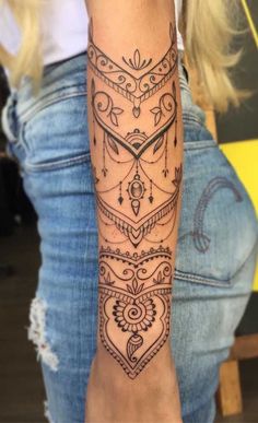 a woman's arm with tattoos on it and an intricate design in the middle