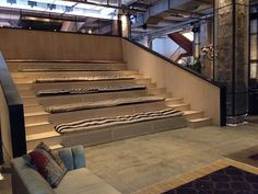 a set of stairs leading up to a living room with couches and rugs