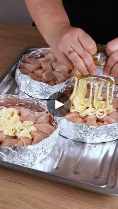 the person is preparing food in foil on the trays and cutting it into smaller pieces