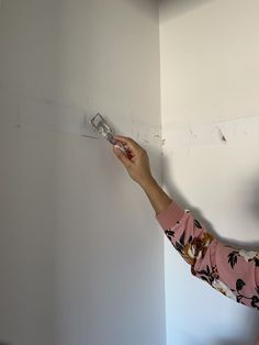 a woman is painting the wall with white paint and she has her hand on it