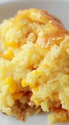 a close up of a plate of food with corn on it and another piece of cake in the background