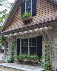 a stone house with plants growing out of the windows and on the front porch area