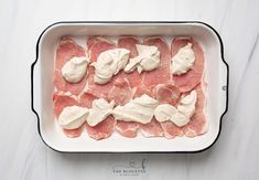 raw meat in a baking dish with cream on top