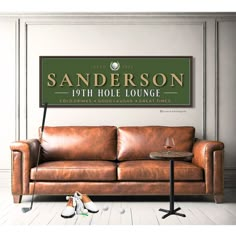 a brown leather couch sitting in front of a sign that says sanders 10th hole lounge