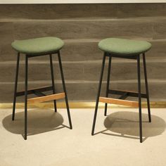 two stools sitting next to each other in front of a wall