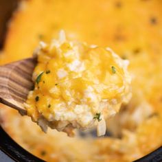 a wooden spoon full of mashed potatoes in a crock pot with broccoli and cheese