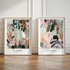 two framed art prints sitting on top of a wooden floor