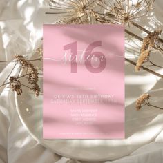 a pink birthday party card on a plate with dried flowers in the background and white linen