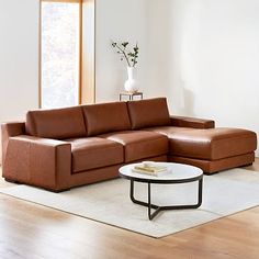 a living room with a couch, coffee table and vase on the floor in front of it