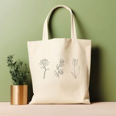 "Our tote bag is perfect for anyone who loves nature-inspired accessories. This floral line art tote bag is trendy and perfect for plant and flower enthusiasts. It is also a great gift for your loved ones who appreciate unique and chic fashion pieces. Whether you're a student, a working professional, or a fashion enthusiast, this tote bag is the perfect addition to your collection. ‣ Tap here to head back to the shop: https://www.etsy.com/shop/FukuDesignsUS ‣ Follow us on: IG - https://www.instagram.com/fukudesignsus/ Pinterest - https://www.pinterest.com/fukudesignsus/ ‣ Reach out to us for any questions that you have about our items. We are here to provide quality products and service to you. SHIPPING AND PRODUCTION TIME Returns are not accepted, but if you do have a concern, please reac Rectangular Bags With Plant Print For Daily Use, Everyday Rectangular Bag With Plant Print, White Botanical Tote Bag, Botanical White Tote Bag, White Botanical Rectangular Bag, Plant Print Tote Bag As Gift, Plant Print Tote Bag For Gift, Botanical Bags With Plant Print For Everyday Use, Botanical Bags With Plant Print And Rectangular Shape