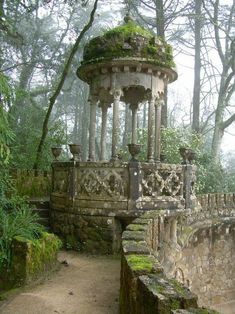 an old stone gazebo with moss growing on it