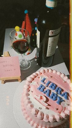 a birthday cake sitting on top of a table next to a wine glass and bottle