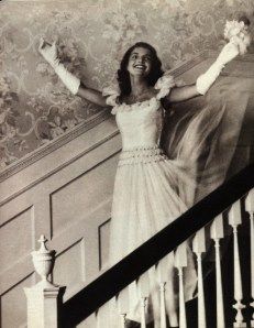 a woman is standing on the stairs with her arms in the air and holding flowers