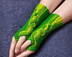 a pair of green knitted fingerless gloves on a woman's arm and hand