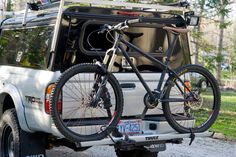 a bike is strapped to the back of a white truck parked in front of trees