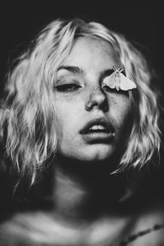 a black and white photo of a woman with a butterfly on her forehead