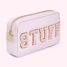 a white cosmetic bag with the word stuiff printed on it and gold zippers