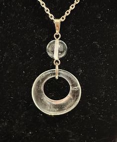 Lovely Coca Cola Live Positively recycled clear glass open round donut-shaped pendant with a clear glass ball above the pendant. The pendant is on an adjustable 17.5" to 20" silver-tone chain, with a silver-tone Coca Cola bottle tag. The necklace and pendant are in good condition, with very slight tarnish. The original Coca-Cola tag is attached. This is a lovely versatile necklace which would complement any outfit and is also eco-friendly. Please message with any questions. Clear Glass Round Pendant Jewelry, Modern Clear Round Jewelry, Adjustable Clear Jewelry, Adjustable Round Clear Jewelry, Clear Glass Pendant Jewelry, Adjustable Clear Necklace, Cola Bottle, Bottle Tags, Coca Cola Bottle