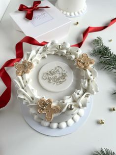 a white plate topped with cookies next to a red ribbon and christmas tree ornaments on top of a table