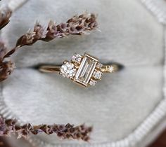 two engagement rings sitting next to each other on top of a white cloth covered surface